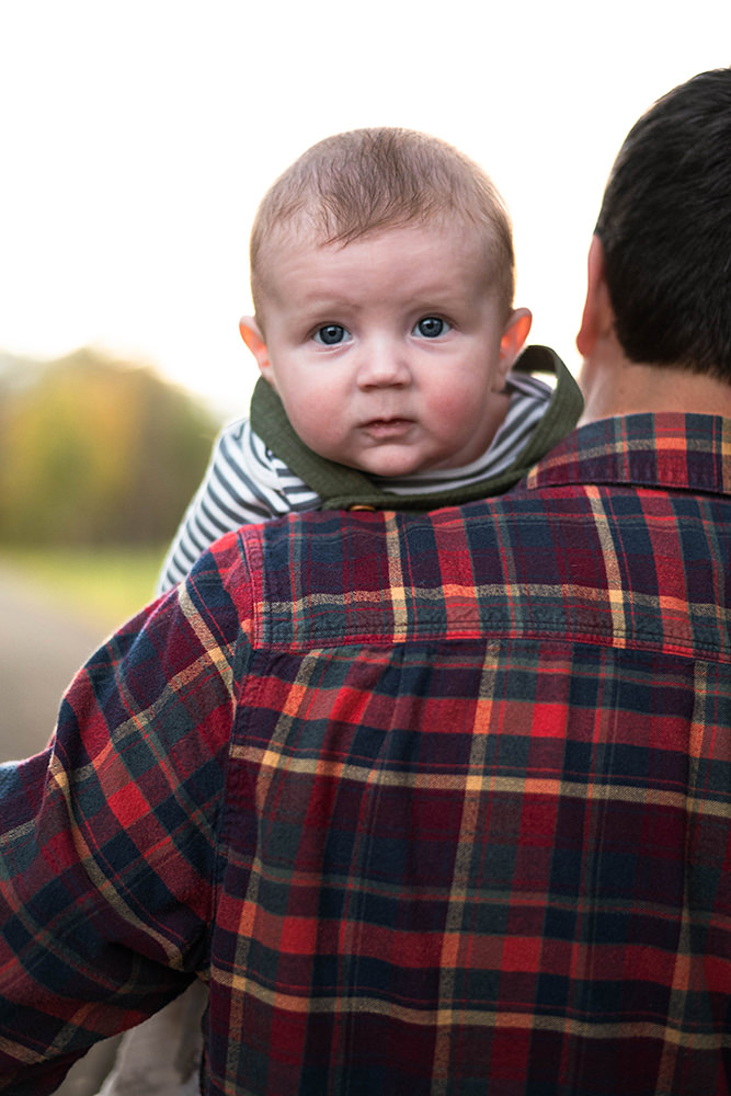 Baby looks over fathers shoulder during family photography session in Schuylerville.