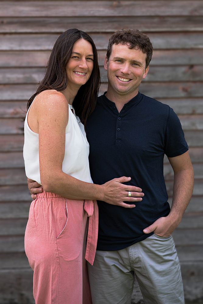 Couple poses in front of a barn