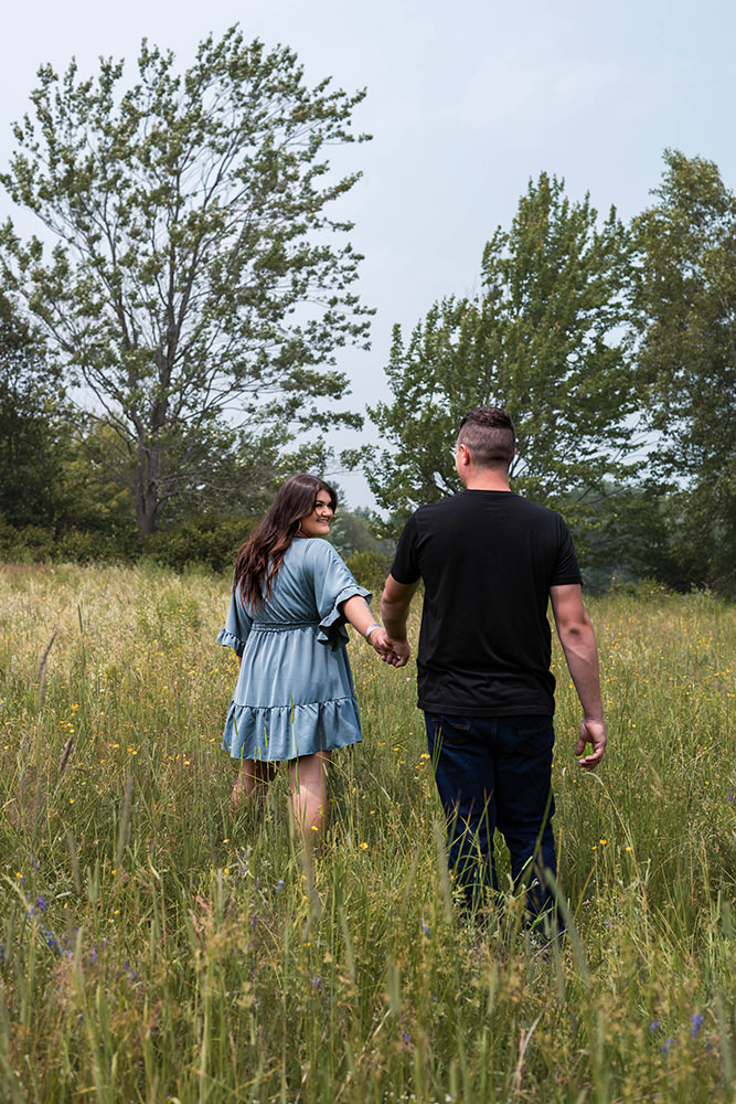 Couple walks through a field during their engagement shoot