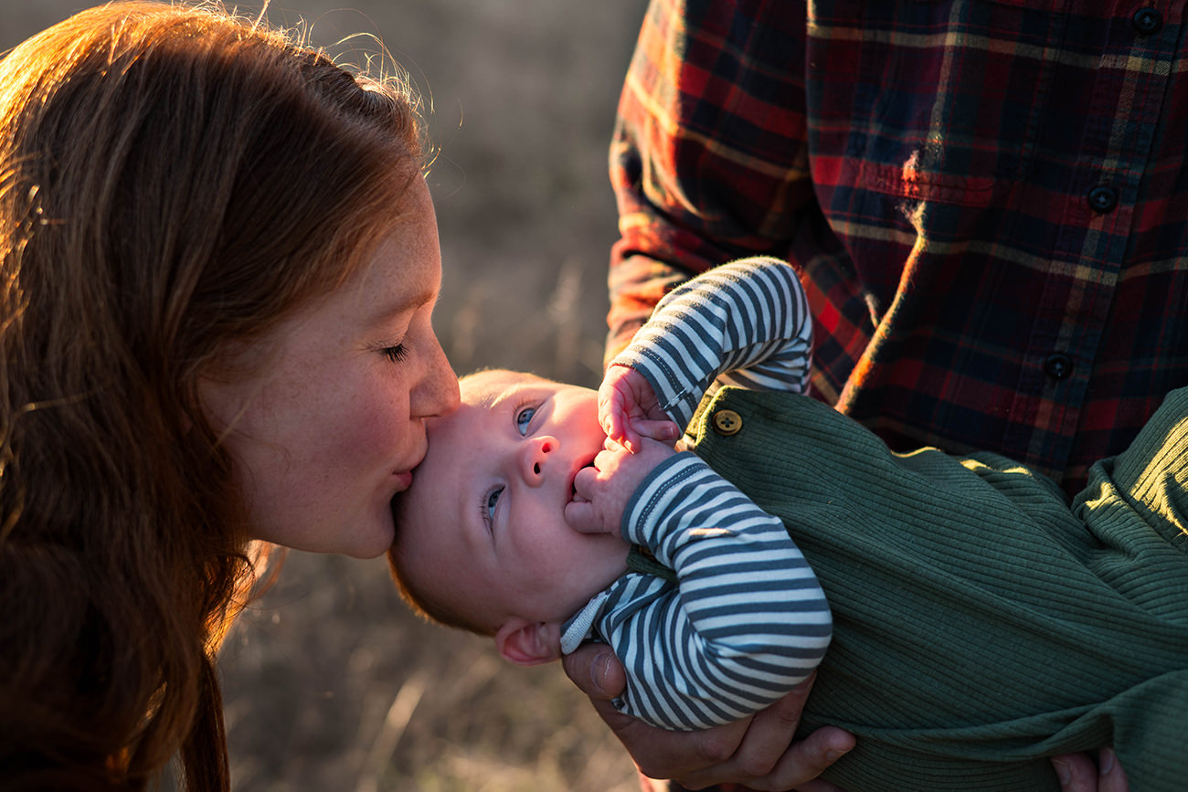 Mother kisses her baby on the head during family photo shoot