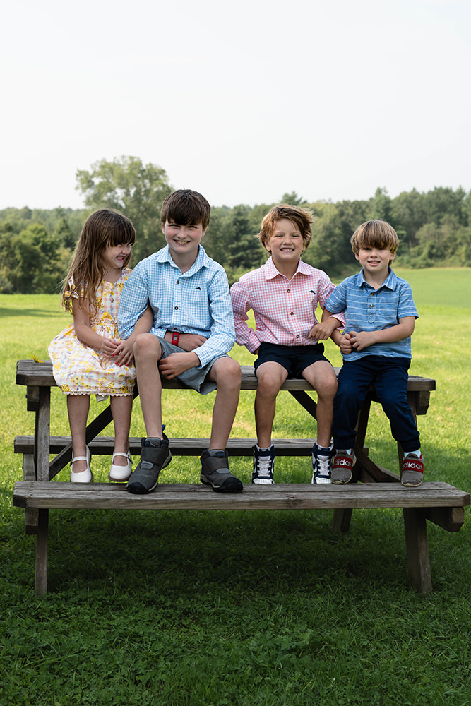 Group of children smile on top of a picnic table during photoshoot