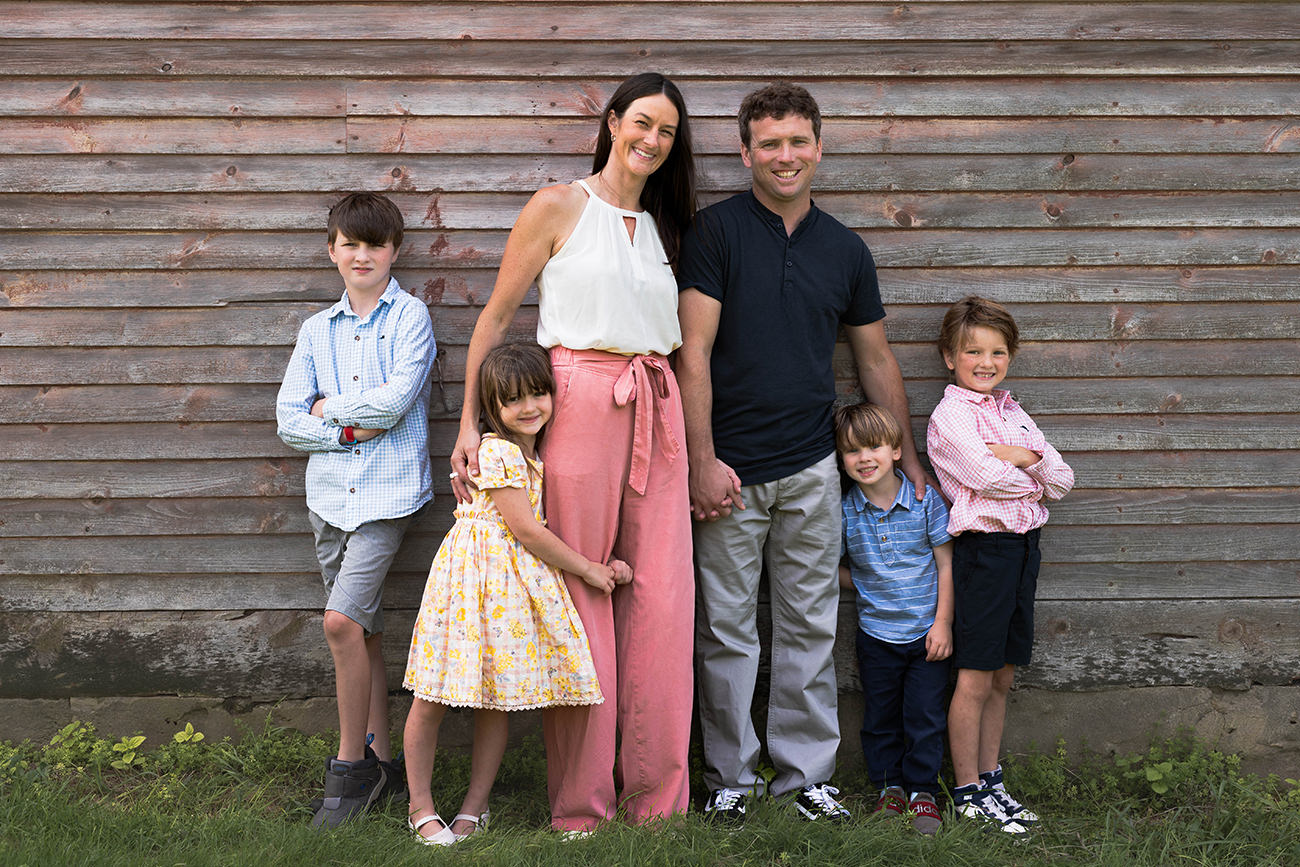 Family poses in front of a barn during their photoshoot