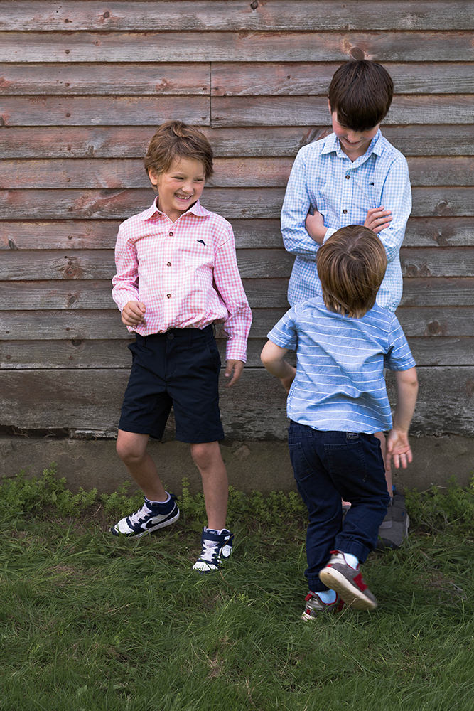 Boy chases his brother causing him to smile during family photo shoot