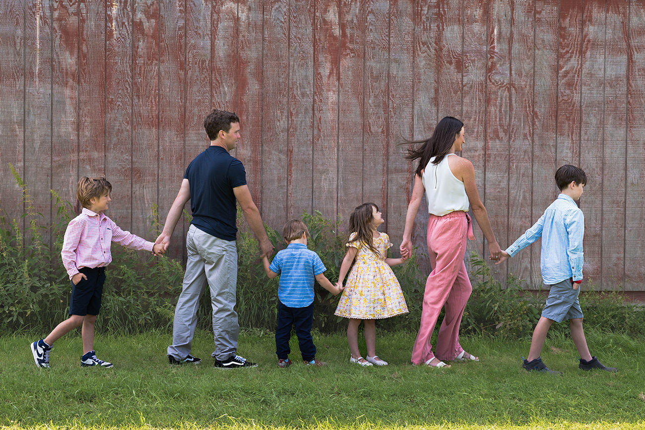 Family lines up arm in arm in front of barn