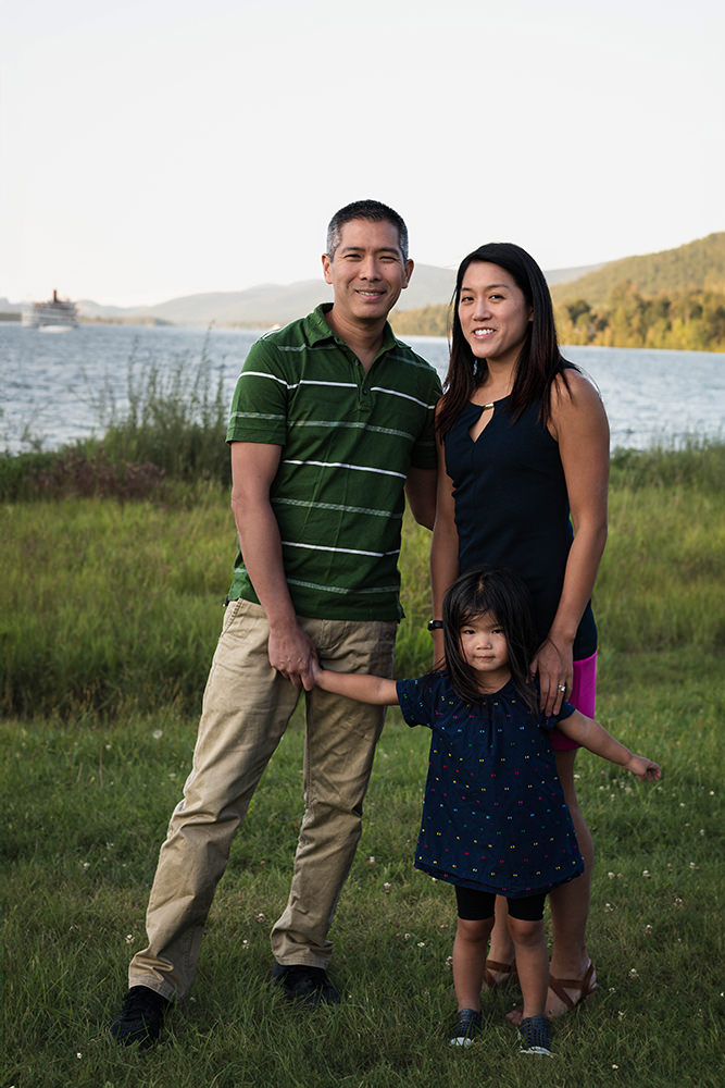 Family stands in front of lake during photoshoot