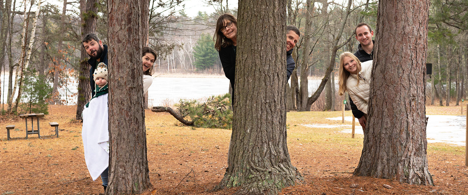 Family poking out from tree for fun photo during family portrait session