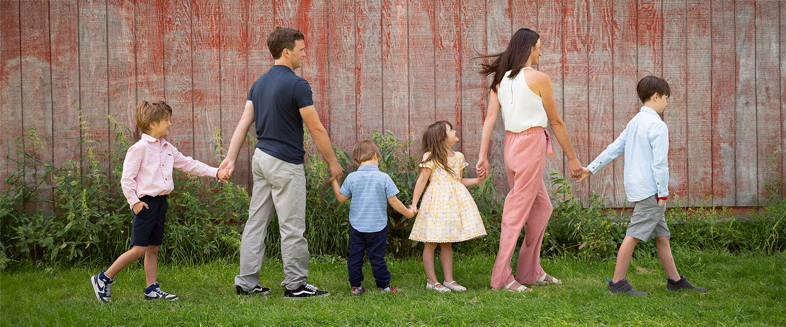 Family lines up arm in arm in front of barn