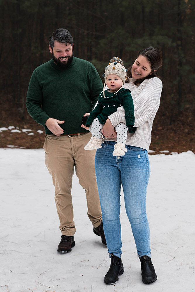 You couple smiles as their baby looks at photographer